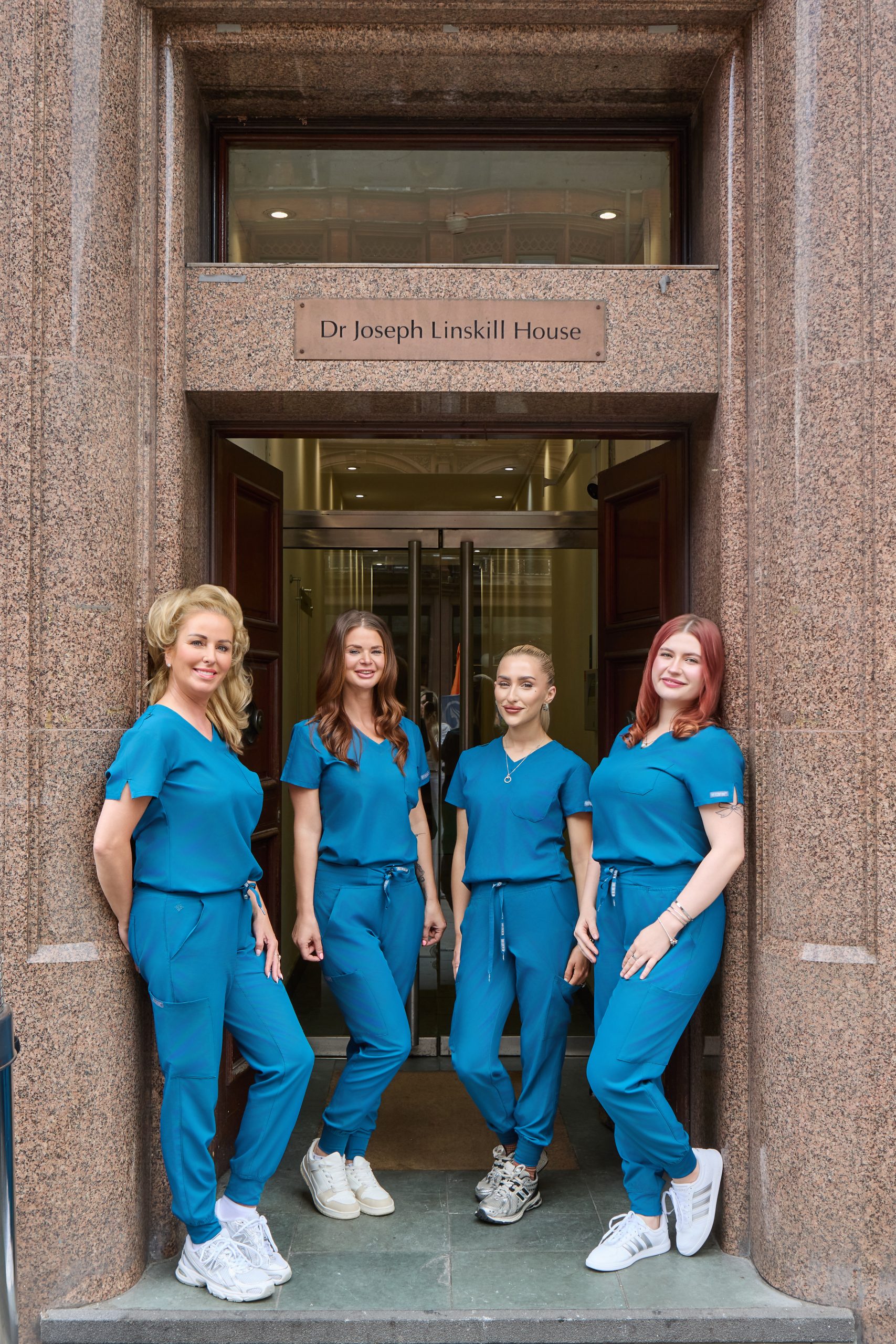 Derma Cosmedic aesthetic team of four in teal scrubs standing outside the Dr Joseph Linskill House entrance on Castle Street, Liverpool